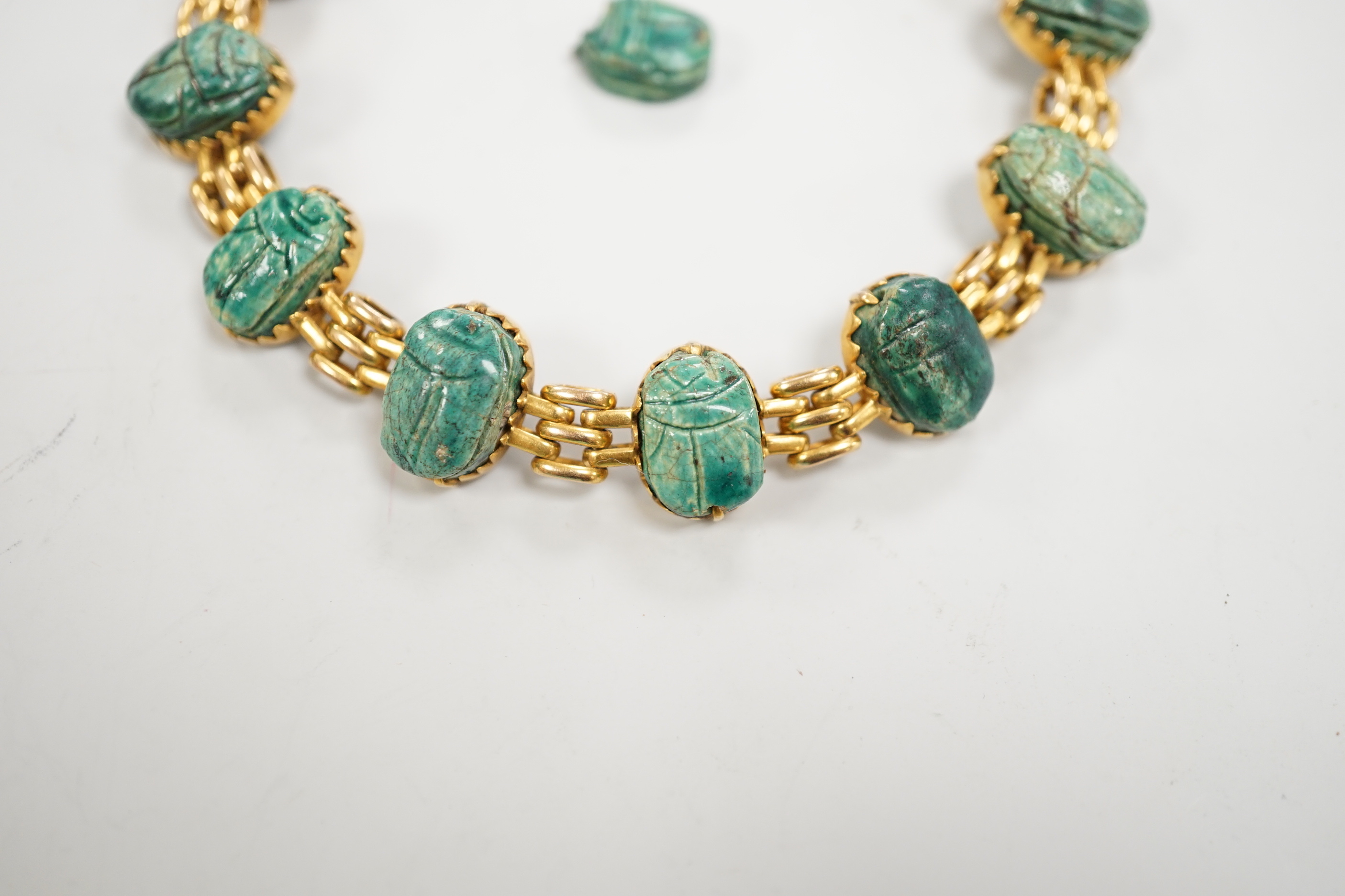 An early 20th century 9ct and ten stone ceramic scarab set bracelet (one stone loose), approx. 17cm, gross weight 20.3 grams.
